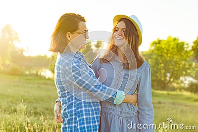 Parent and teenager, mother and 14 year old daughter embrace smiling in nature. Stock Photo