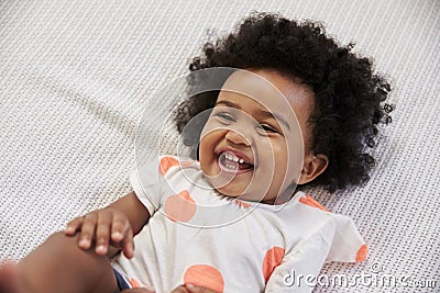 Parent Tickling Laughing Baby Girl Lying On Bed Stock Photo