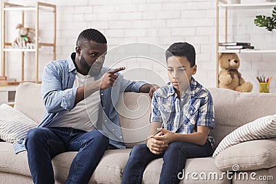 Parent Violence. Angry Black Father Scolding His Upset Innocent Son Stock Photo