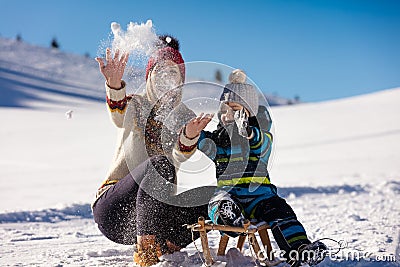 Parenthood, fashion, season and people concept - happy family with child on sled walking in winter outdoors Stock Photo