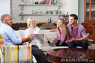 Parents With Adult Offspring Using Digital Devices At Home Stock Photo