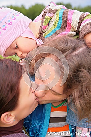 Parents with baby kiss outdoor Stock Photo