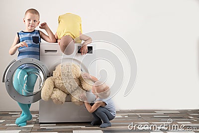 Parents bought a new washing machine. The children try to turn it on and wash the soft toys. Happy boys are playing at home Stock Photo