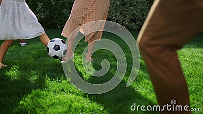 Parents and children feet playing football. Father throwing soccer ball in air Stock Photo