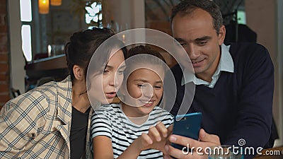 Parents and daughter are viewing photos on the phone at lunch Stock Photo