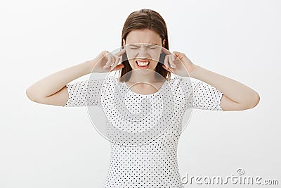 Parents fighting again, girl frowning and grimacing, clenching teeth while trying to close ears with index fingers Stock Photo
