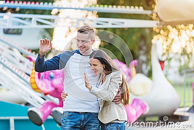 Parents at fun fair, waving their child taking ride Stock Photo