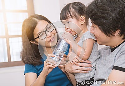 Parents giving little daughter a bottle with drink Stock Photo