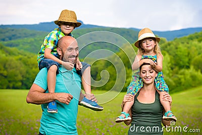 Parents giving piggyback ride to children, happy family Stock Photo