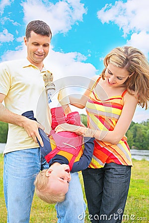 Parents hold child beneath by head Stock Photo