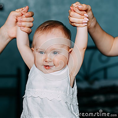Parents hold hands of a small smiling girl Stock Photo