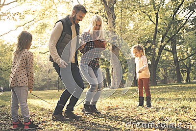 Parents jumping across jump rope little girl holding rope in Stock Photo