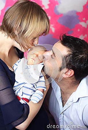 Parents kissing newborn baby Stock Photo