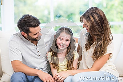 Parents looking at daughter while sitting on sofa Stock Photo