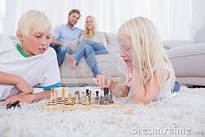 Parents looking at their children playing chess Stock Photo