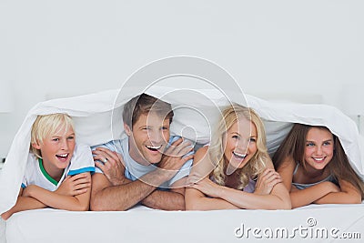 Parents lying on bed with their children Stock Photo