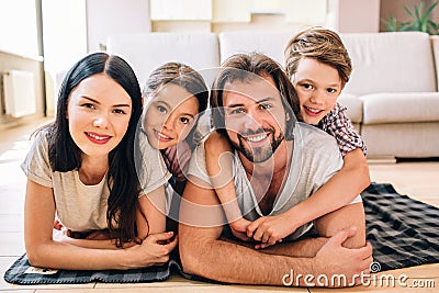 Parents are lying on the floor. Kids are on them. Children are hugging their parents. All of them are positive. They Stock Photo
