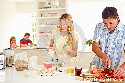 Parents Preparing Family Breakfast In Kitchen Stock Photo