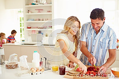 Parents Preparing Family Breakfast In Kitchen Stock Photo