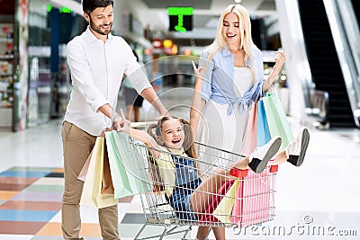 Parents Riding Excited Daughter In Shopping Cart Walking In Mall Stock Photo