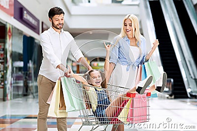 Parents Riding Happy Daughter In Shopping Cart In Mall Stock Photo