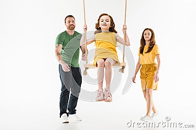 Parents riding little happy daughter on swing Stock Photo