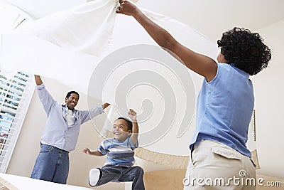 Parents Spreading Bedsheet Over Son Stock Photo