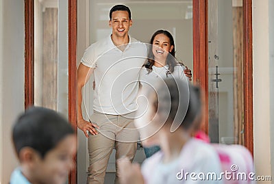 Parents standing at their front door and seeing off school children. Caring parents watching their son and daughter Stock Photo