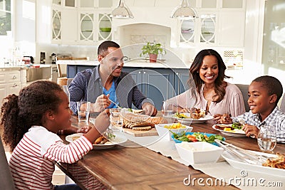 Parents and their two children eating at kitchen table Stock Photo