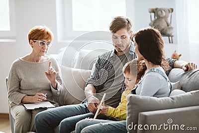 Parents and therapist are sitting on the couch talking about their child Stock Photo