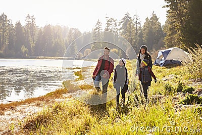 Parents and two children on camping trip walking near a lake Stock Photo