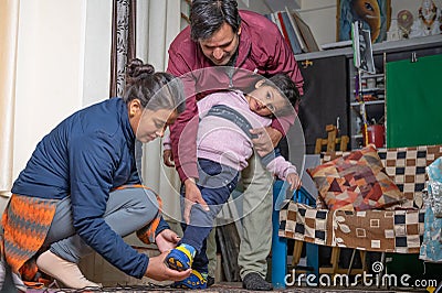 Parents wearing shoes to their child Stock Photo