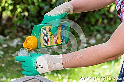 Paris, France - August 15, 2018 : Gardener using Roundup herbicide in a french garden. Roundup is a brand-name of an herbicide con Editorial Stock Photo