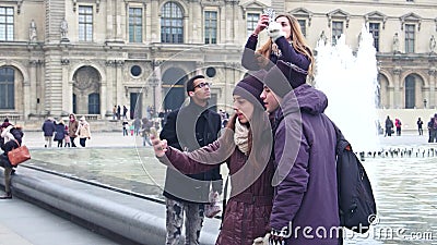 PARIS, FRANCE - DECEMBER, 31, 2016. Multiethnic couples making selfies near the Louvre glass pyramid and fountains Editorial Stock Photo