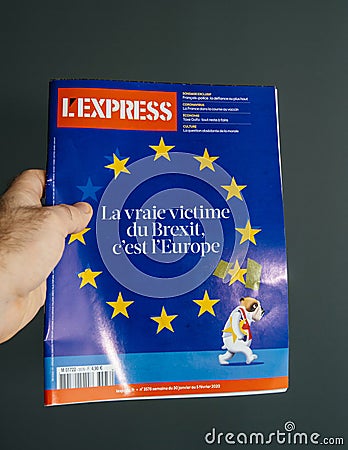 Male hand holding L`Express newspaper magazine with cover of old bulldog leaving Editorial Stock Photo