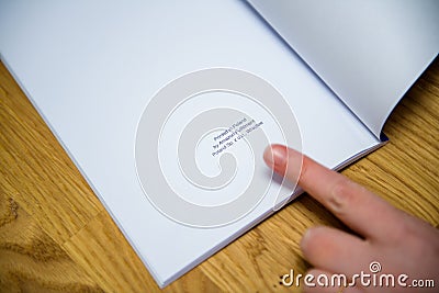 POV woman showing with the finger the text at the end of the book Printed in Editorial Stock Photo