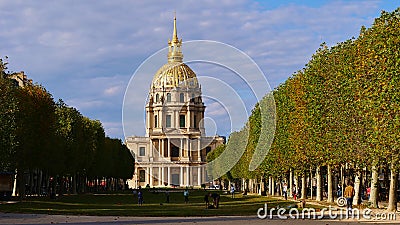 Front view of historic Les Invalides dome with golden colored cupola framed by a symmetric arrangement of trees. Editorial Stock Photo