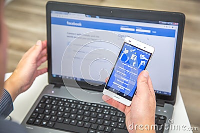 Paris, France - January 27, 2017 : Man connecting on french Facebook with his smartphone and laptop. As of today, Facebook is the Editorial Stock Photo