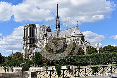 Paris, France. Notre Dame Cathedral from bridge over Seine river. Trees and river walk. Blue sky with clouds. Stock Photo