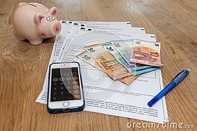 Paris, France - November 15, 2018 : The various French taxes return, piggy bank and banknotes in euros Editorial Stock Photo