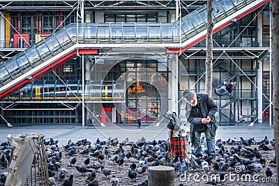 PARIS - January 4, 2016: Unidentified elderly man feeding pigeon Editorial Stock Photo