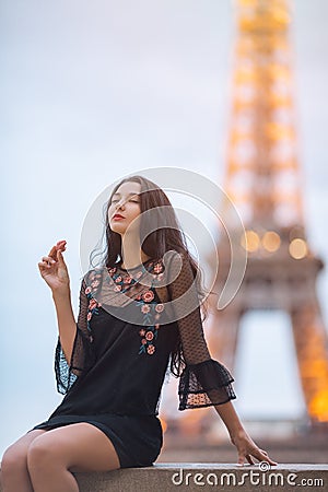 Paris woman smiling eating the french pastry macaron in Paris against Eiffel tower. Stock Photo