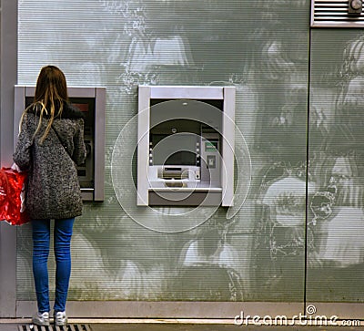 Parisian young woman makes monetary transaction in street ATM Editorial Stock Photo