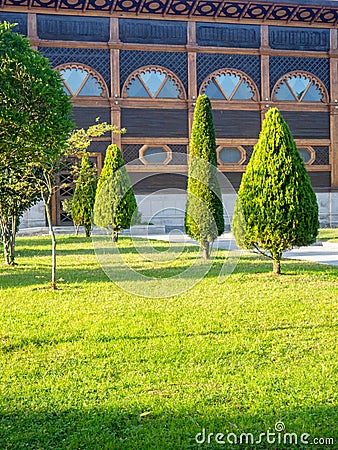 Park area. Well-groomed lawn of the park. Wooden architecture and topiary bushes Stock Photo