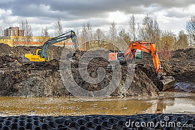Two powerful excavators dig a pond in the park Editorial Stock Photo