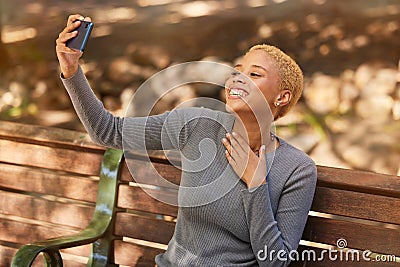 Park bench, phone selfie and black woman in nature outdoors taking picture. Happy, smile and girl from South Africa with Stock Photo