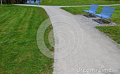 Park benches in light blue made of metal strips similar to a lattice. trash can and beautiful lawn with park paths of gravel thres Stock Photo