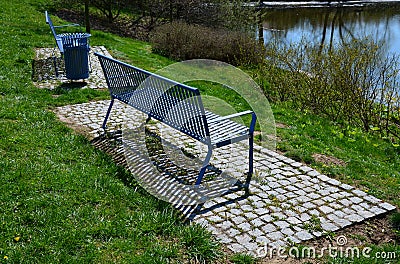 Park benches in light blue made of metal strips similar to a lattice. trash can and beautiful lawn with park paths of gravel thres Stock Photo