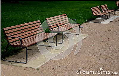Park benches lined with wood along the entire wide threshing gravel beige path, lawns, flower lush, perennial flower beds blooming Stock Photo