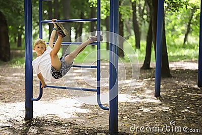 In the park on the sports ground, the boy climbed the stairs and hung with his legs hooked Stock Photo